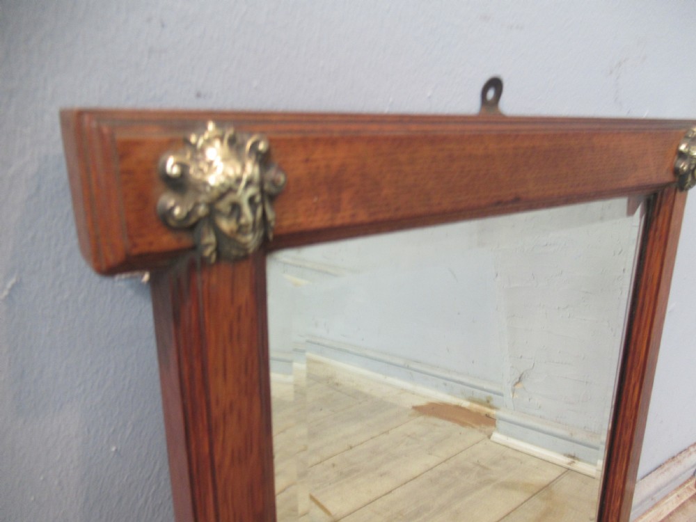 A late Victorian oak framed wall mirror featuring top brass corner mounts and an integrated lower shelf. View III