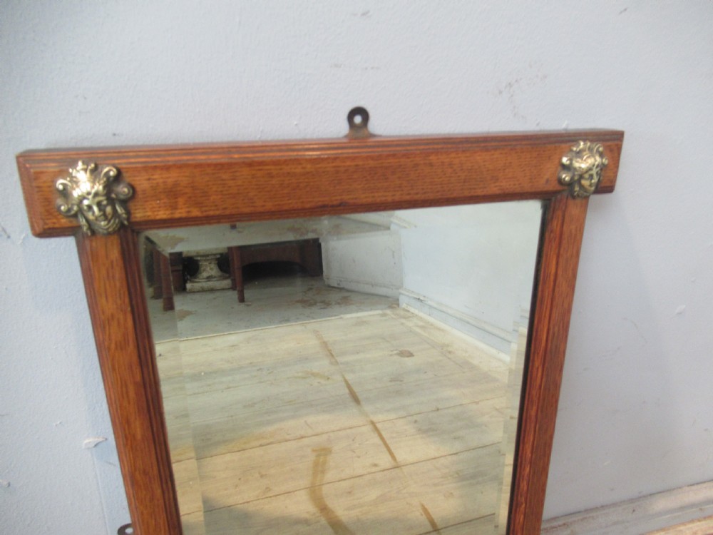 A late Victorian oak framed wall mirror featuring top brass corner mounts and an integrated lower shelf. View IV