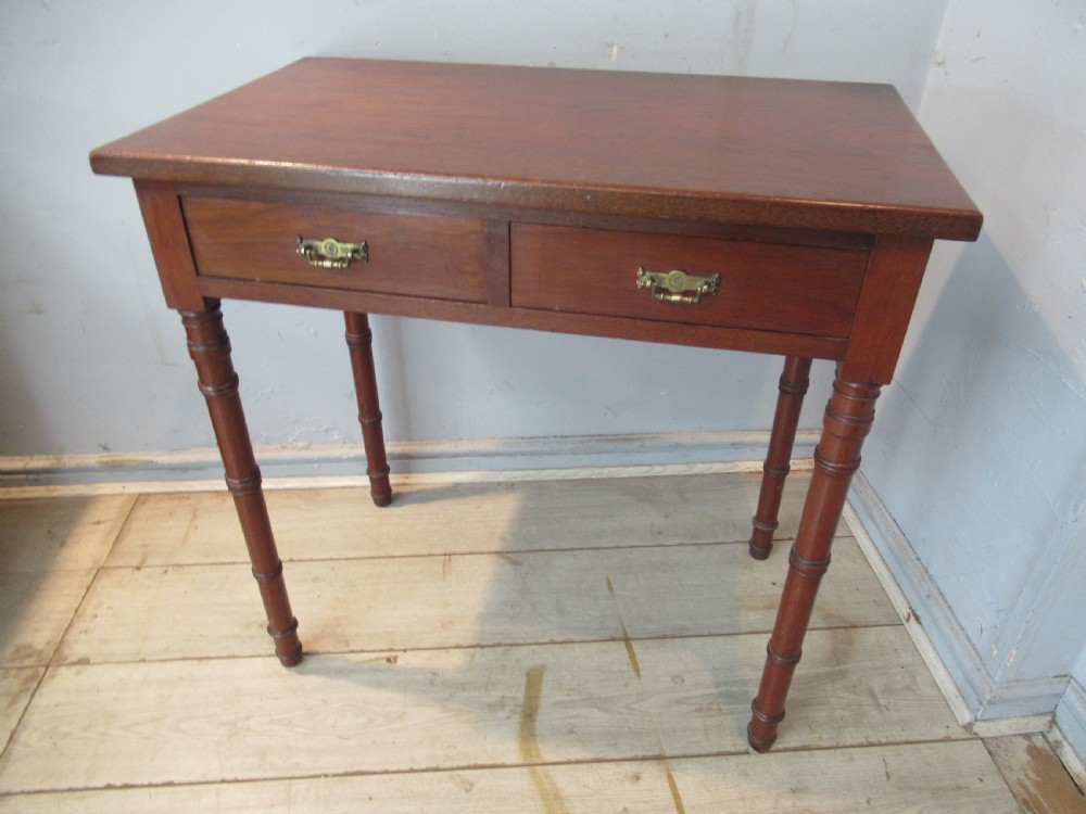 A late Victorian mahogany side table featuring two drawers with brass drop handles and four ring-turned bamboo-style legs.