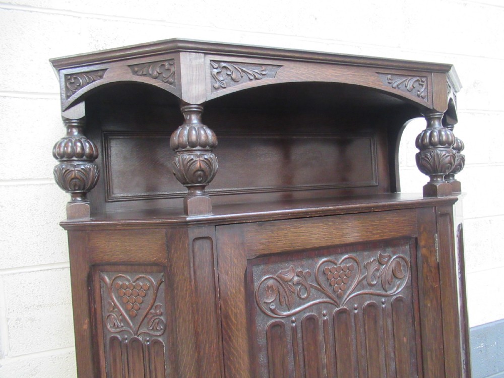 A dark oak corner hall wardrobe featuring carved decorative panels, turned gallery pillars, and a single hinged door. View IV