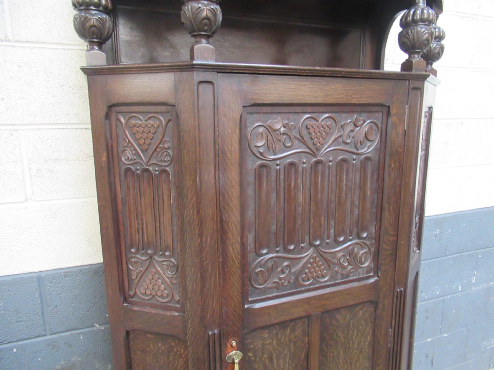 A dark oak corner hall wardrobe featuring carved decorative panels, turned gallery pillars, and a single hinged door. View V