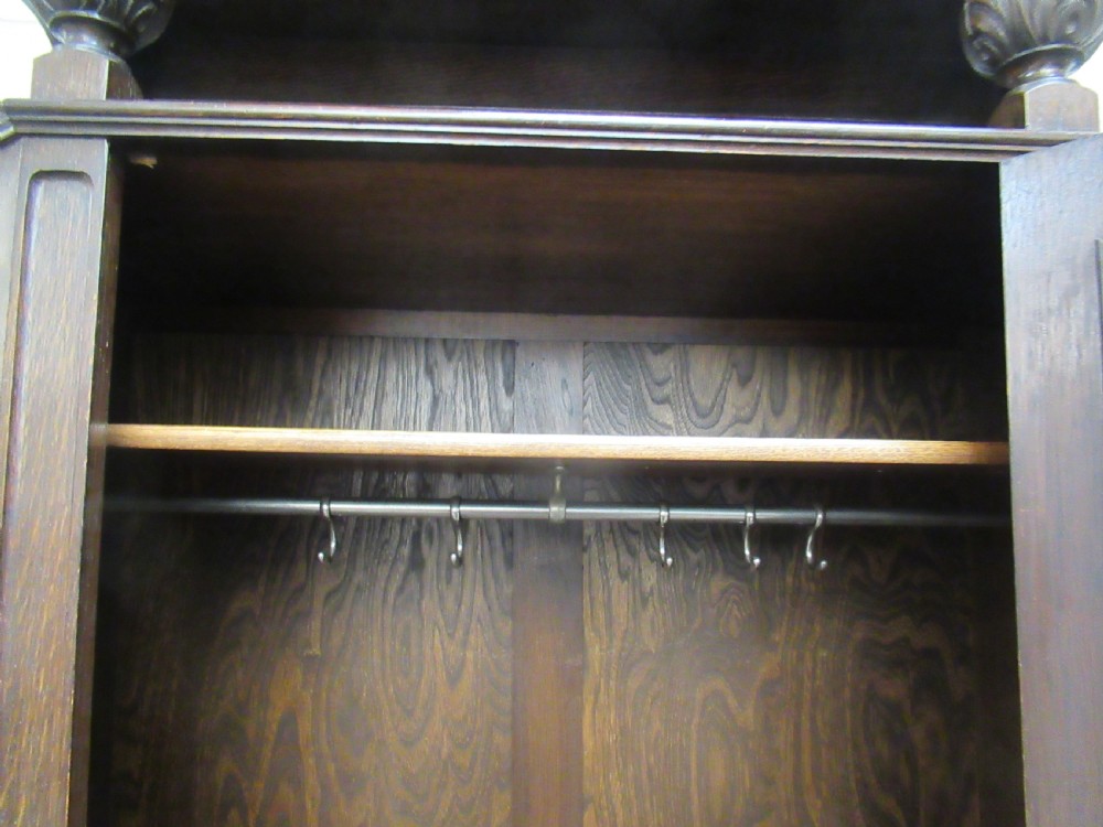 A dark oak corner hall wardrobe featuring carved decorative panels, turned gallery pillars, and a single hinged door. View VIII