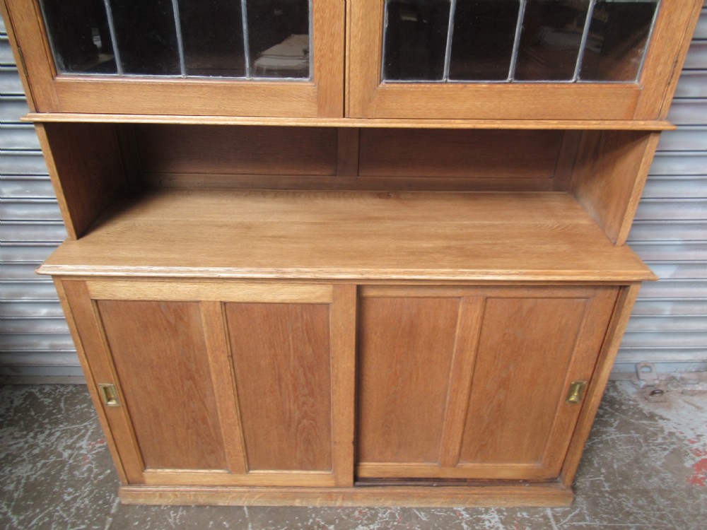 A light oak glazed dresser featuring leaded glass upper doors and a lower section with sliding panelled doors. View VI