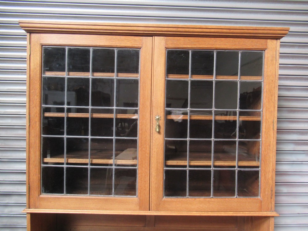A light oak glazed dresser featuring leaded glass upper doors and a lower section with sliding panelled doors. View VII