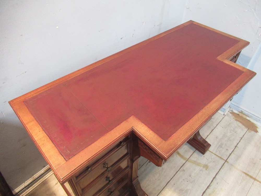 A late Victorian walnut pedestal desk featuring a dark leather writing inset, multiple burr walnut drawer fronts with brass knobs, and fluted column accents. View XII