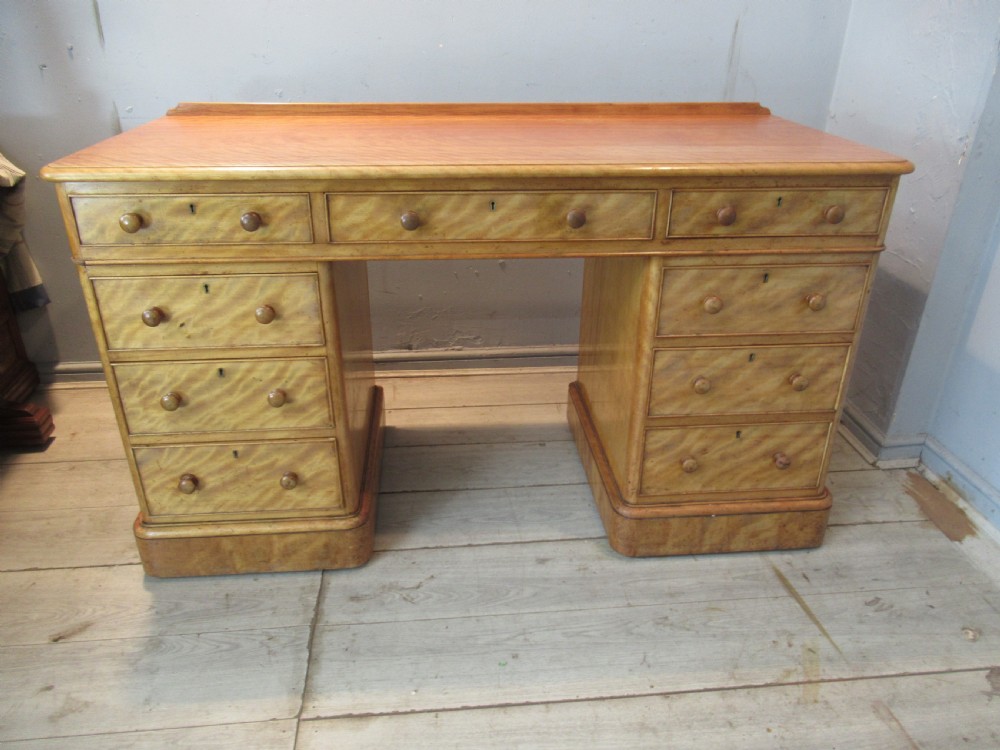 A Victorian satin birch kneehole desk featuring nine drawers with turned wooden handles and a solid plinth base. View II