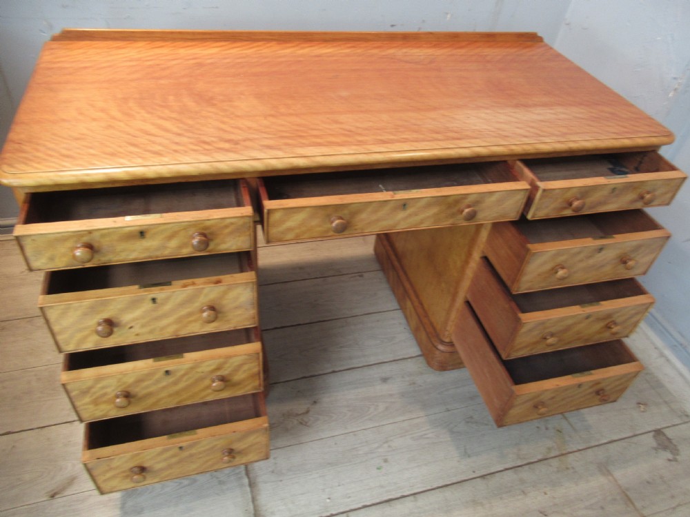 A Victorian satin birch kneehole desk featuring nine drawers with turned wooden handles and a solid plinth base. View IX