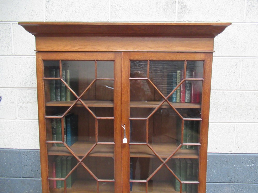 A 1920s warm brown oak cupboard bookcase featuring two upper glazed doors with geometric astragal glazing, two drawers, and a two-door lower cupboard. View VIII