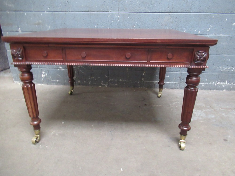 An early nineteenth century mahogany extending library desk with side pull-out trays, reeded turned legs, and brass castors. View II