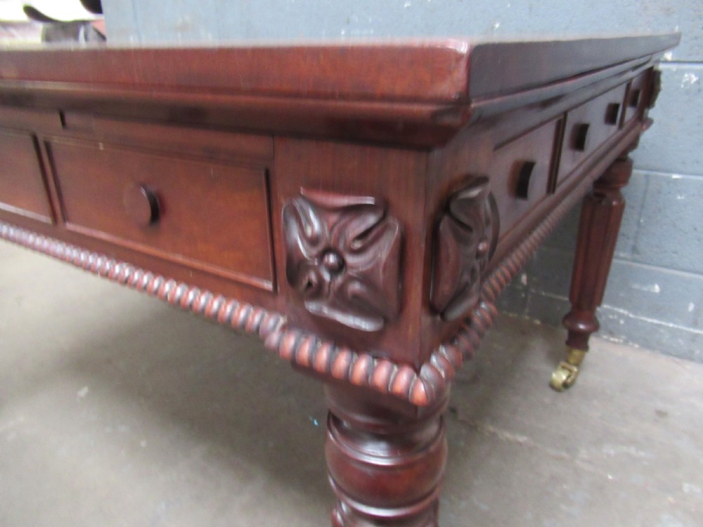 An early nineteenth century mahogany extending library desk with side pull-out trays, reeded turned legs, and brass castors. View IV