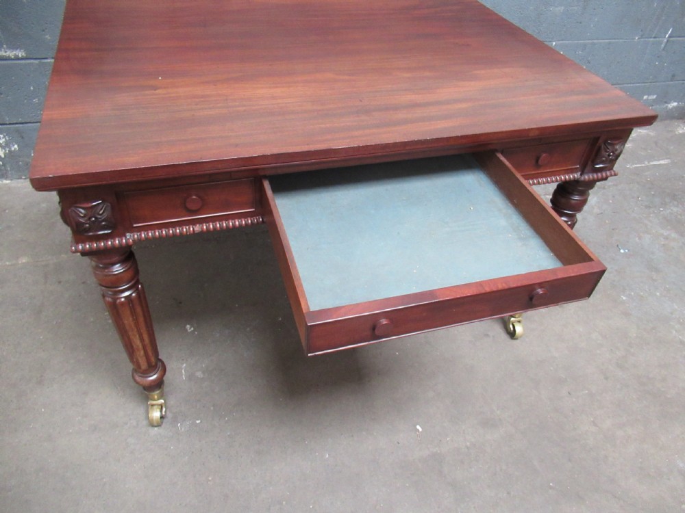 An early nineteenth century mahogany extending library desk with side pull-out trays, reeded turned legs, and brass castors. View VI
