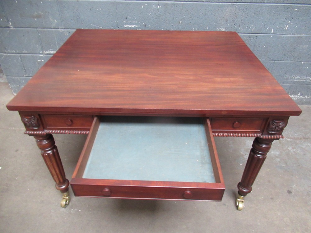 An early nineteenth century mahogany extending library desk with side pull-out trays, reeded turned legs, and brass castors. View VII