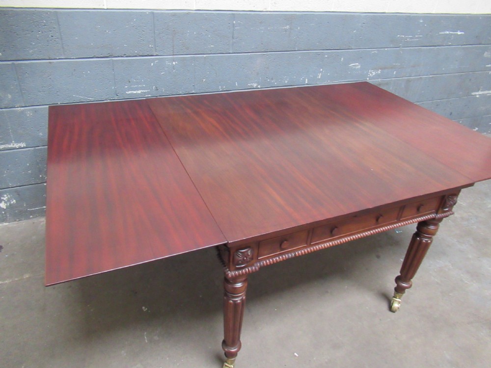 An early nineteenth century mahogany extending library desk with side pull-out trays, reeded turned legs, and brass castors. View IX