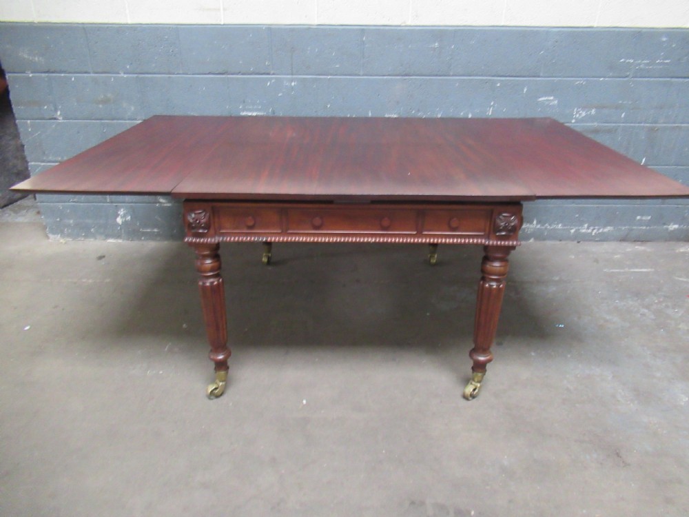 An early nineteenth century mahogany extending library desk with side pull-out trays, reeded turned legs, and brass castors. View XI