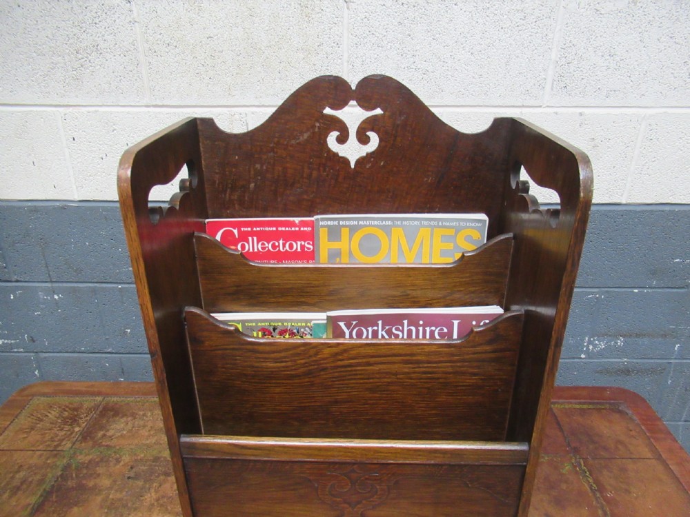 A freestanding 1920s oak magazine rack with cut-out carry handles, pierced decorative motifs, and three internal compartments. View VI