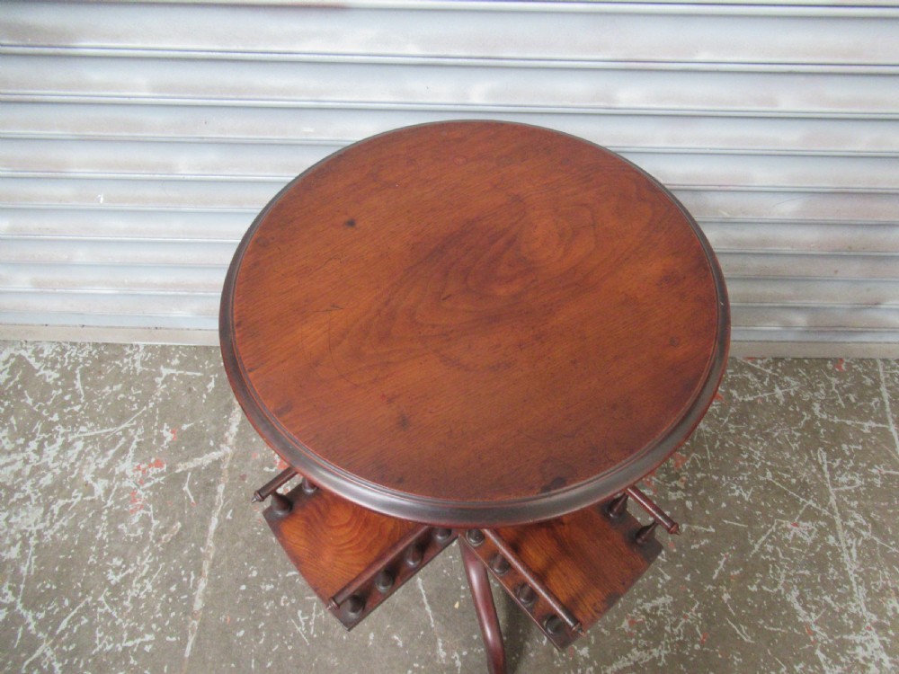 A late Victorian dark mahogany revolving book stand featuring a circular top, turned central column, spindle-galleried compartments, and a tripod base. View III