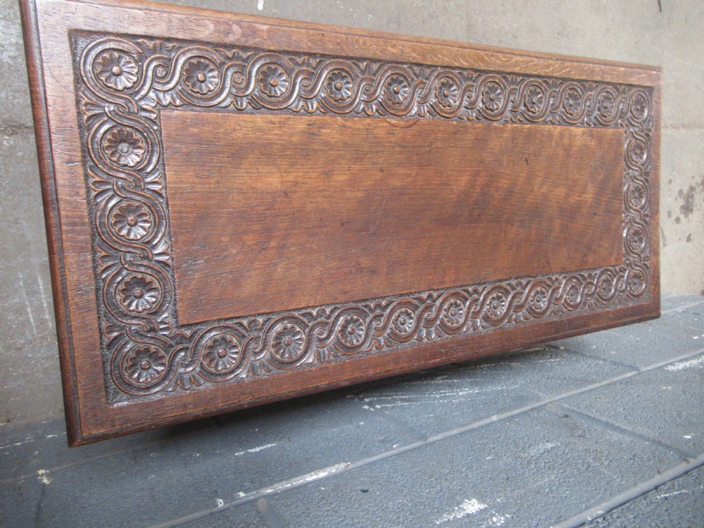 A late Victorian carved oak lidded box featuring relief foliate scrollwork on the front panel and raised on carved side supports. View X