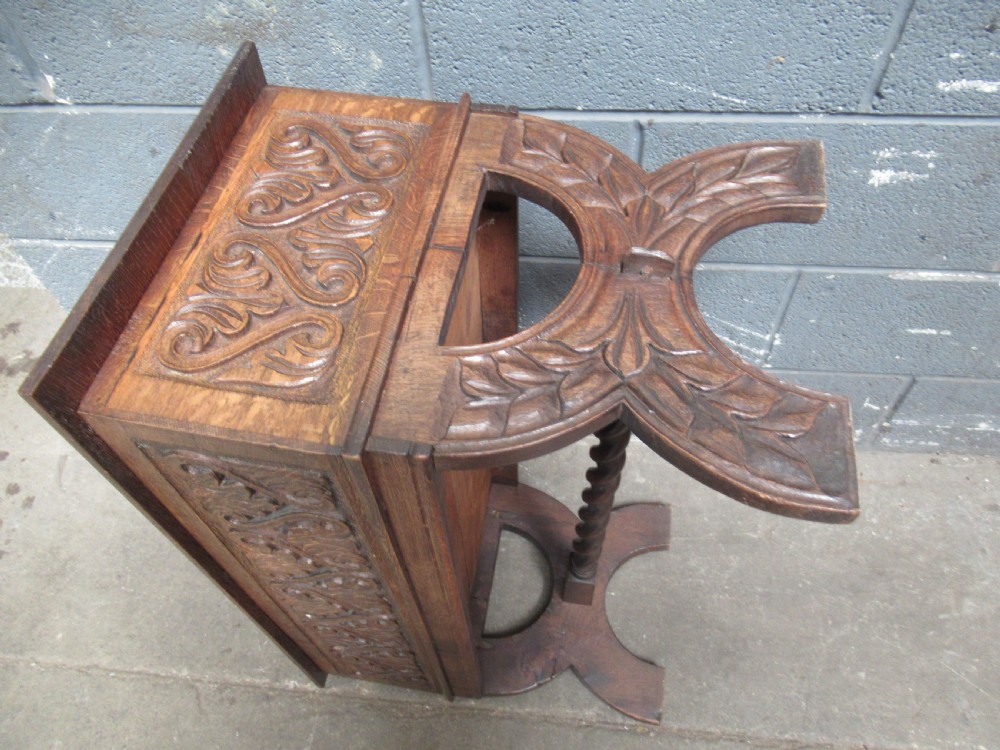 A late Victorian carved oak lidded box featuring relief foliate scrollwork on the front panel and raised on carved side supports. View XII