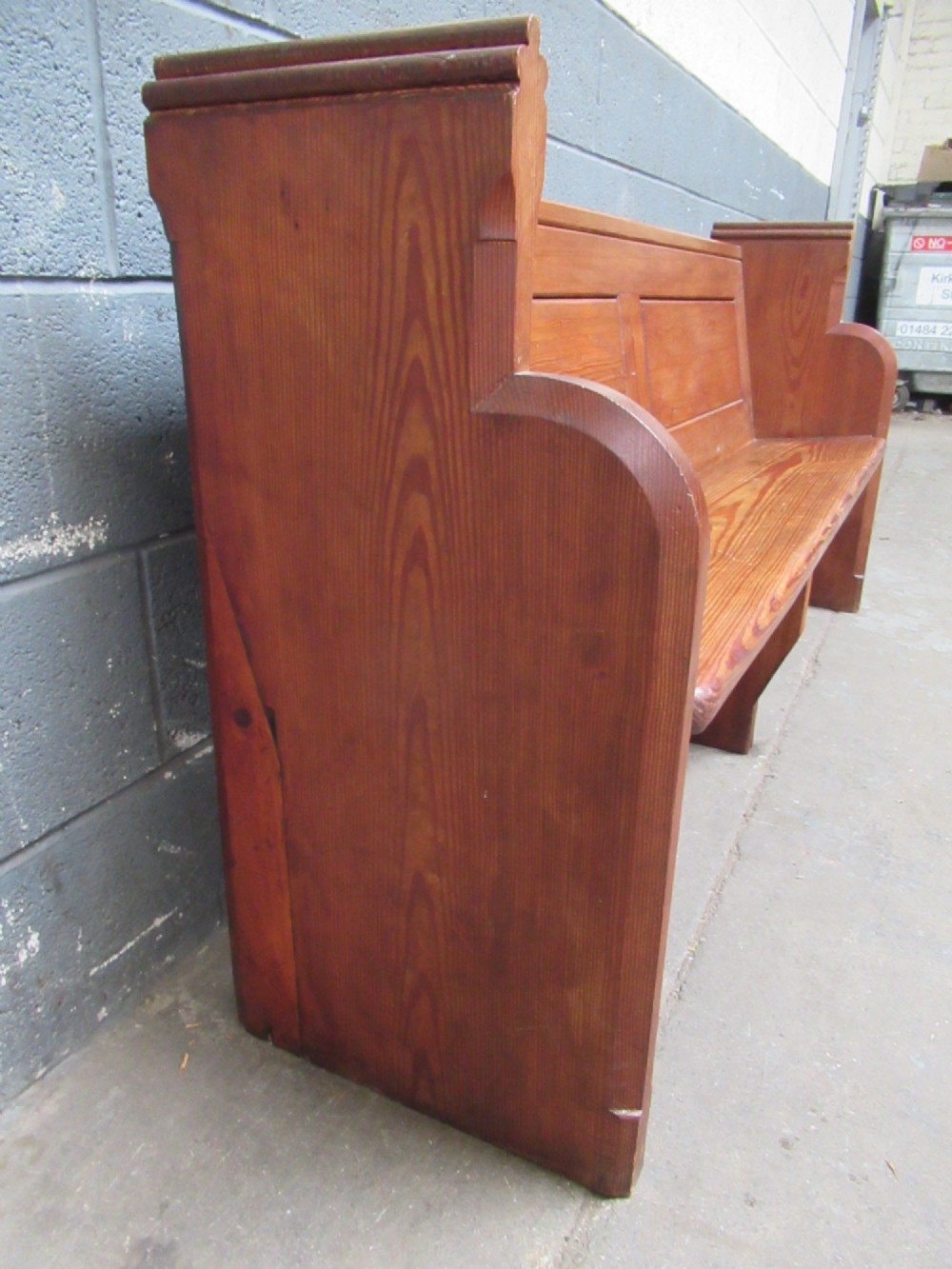 A long Victorian pitch pine church pew bench featuring a panelled back rest and carved end supports. View VII