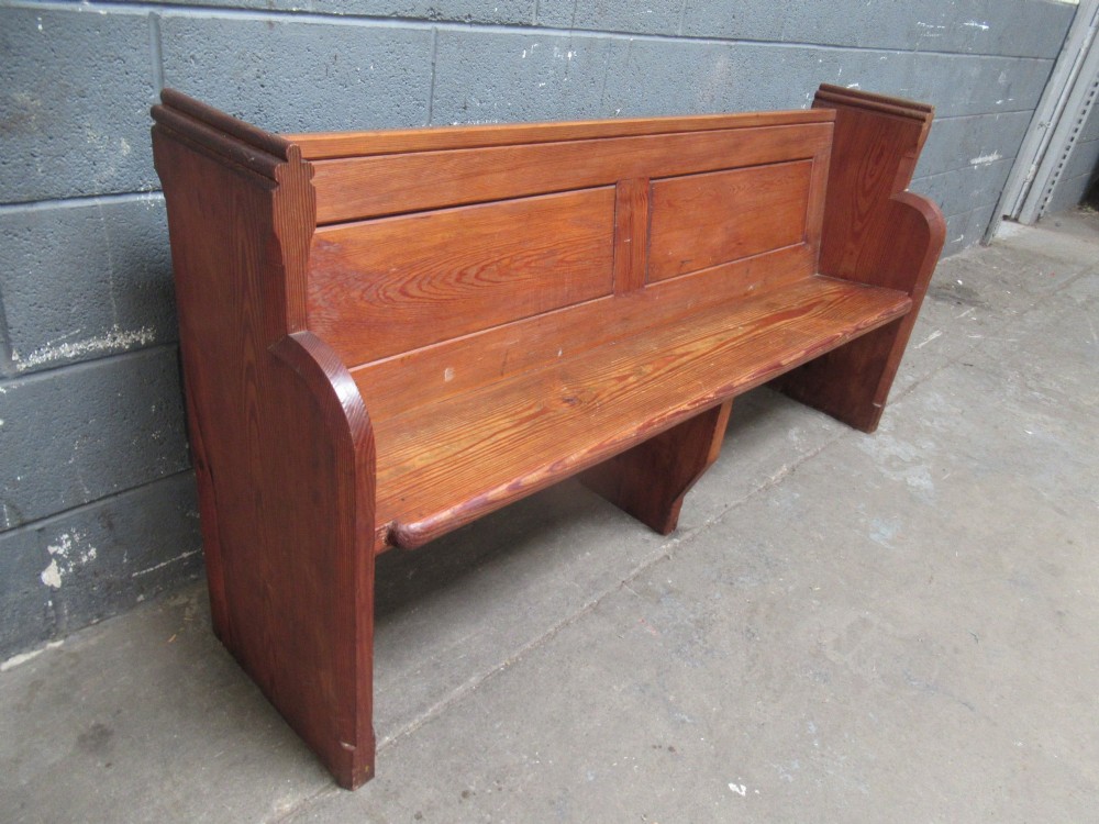 A long Victorian pitch pine church pew bench featuring a panelled back rest and carved end supports. View VIII
