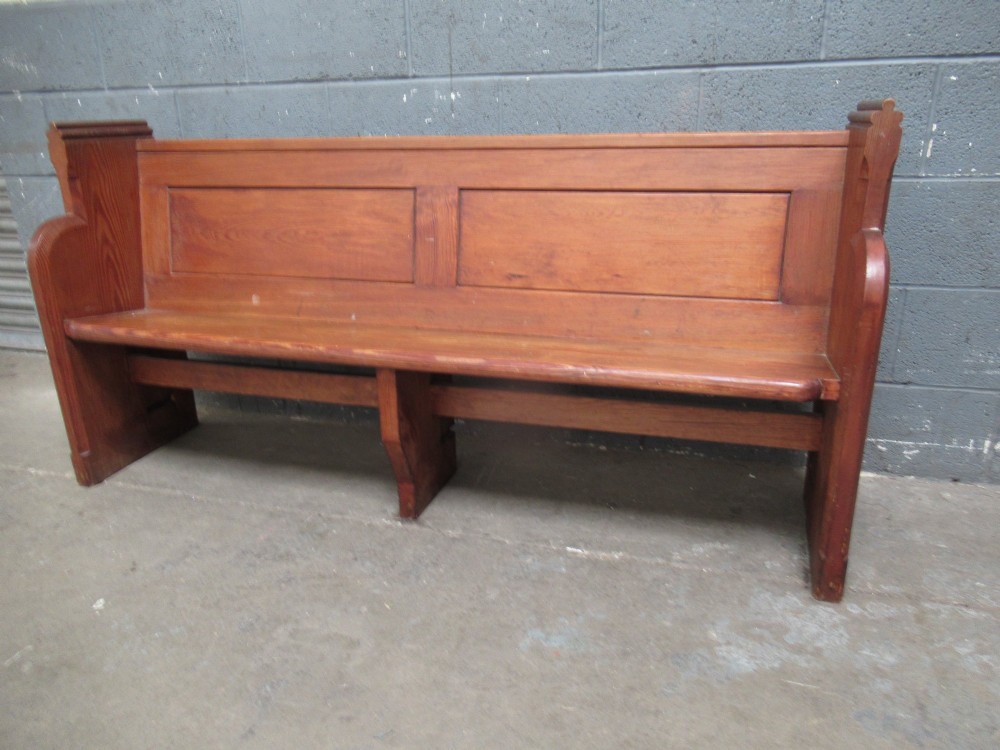 A long Victorian pitch pine church pew bench featuring a panelled back rest and carved end supports. View IX