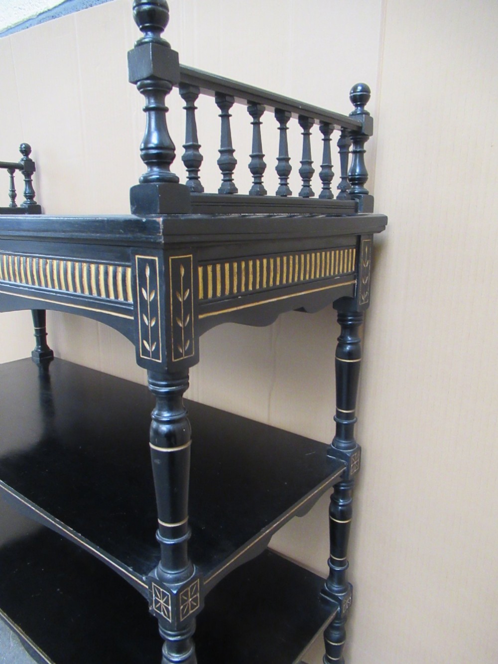 Victorian ebonised three-tier side table featuring spindle side galleries, turned legs, brass castors, and gold fluted detailing on the frieze. View VII