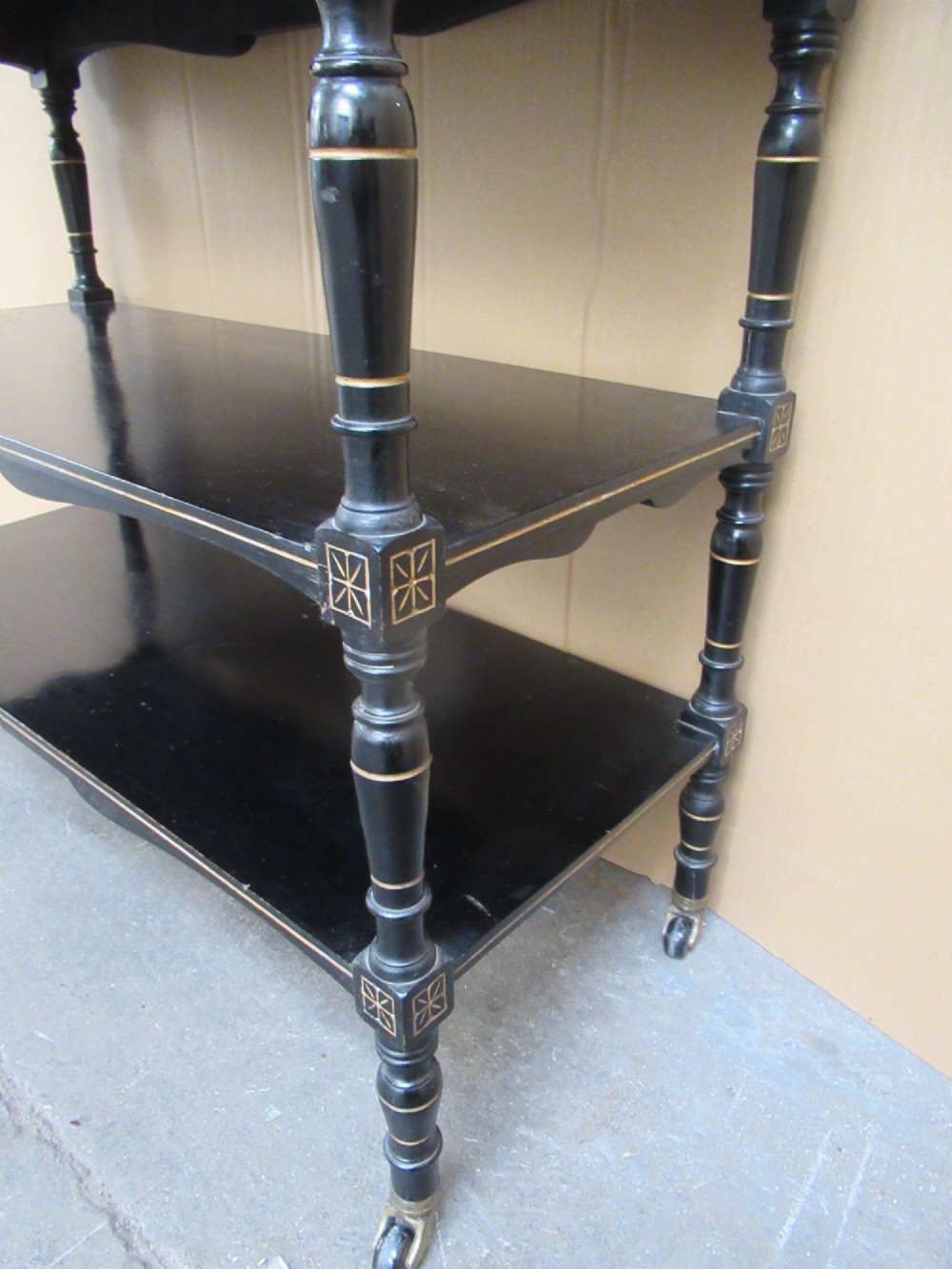 Victorian ebonised three-tier side table featuring spindle side galleries, turned legs, brass castors, and gold fluted detailing on the frieze. View VIII