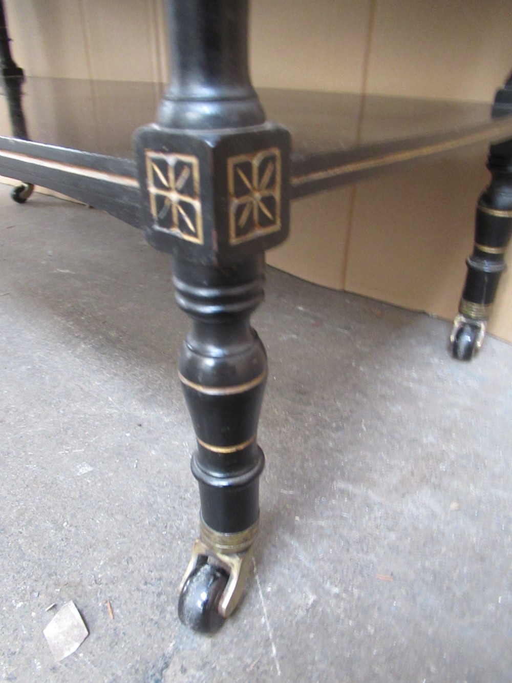 Victorian ebonised three-tier side table featuring spindle side galleries, turned legs, brass castors, and gold fluted detailing on the frieze. View IX