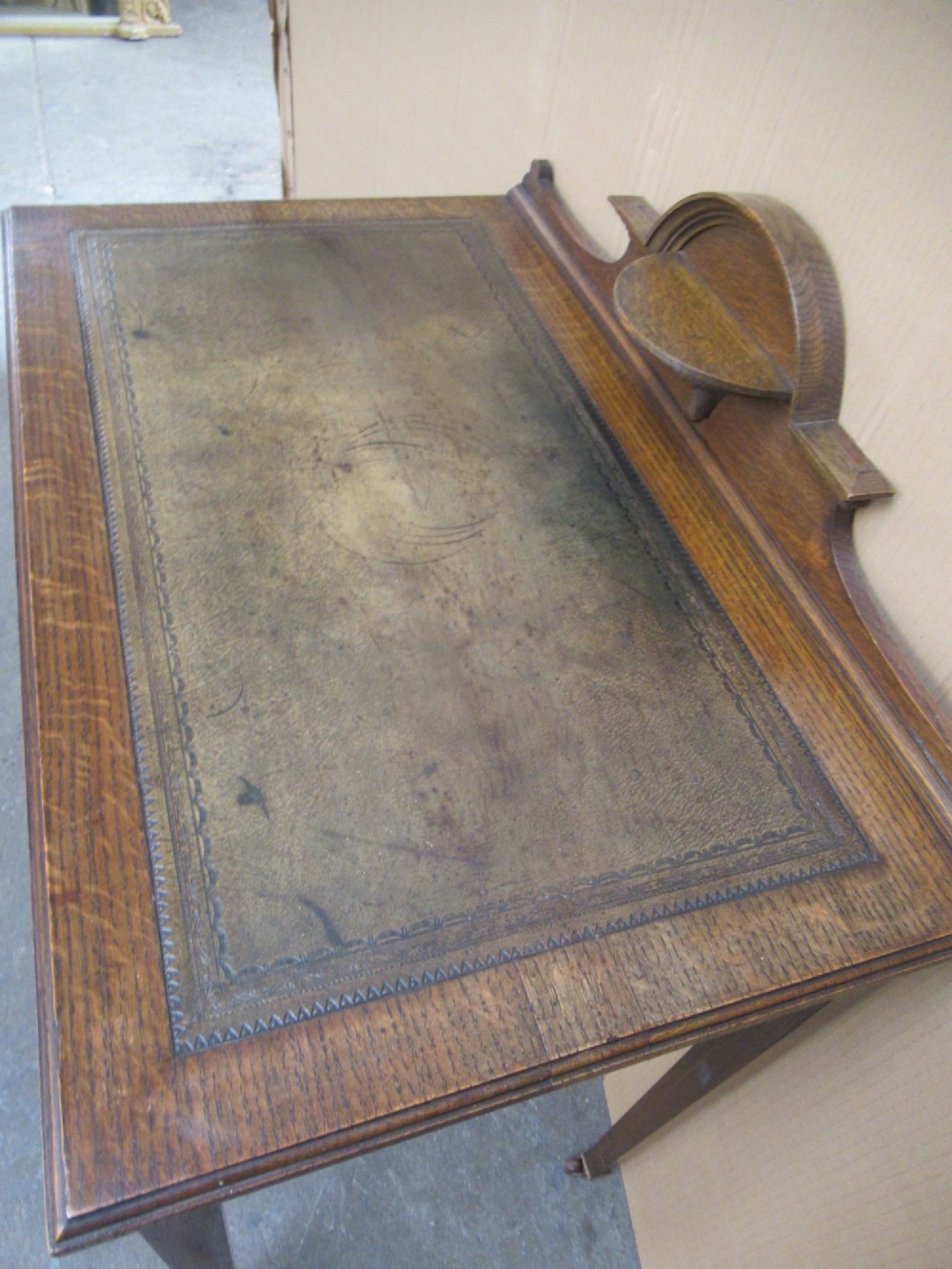 An Edwardian oak writing desk with a leather inset top, three drawers with brass handles, and a raised gallery back featuring a small bracket shelf. View V