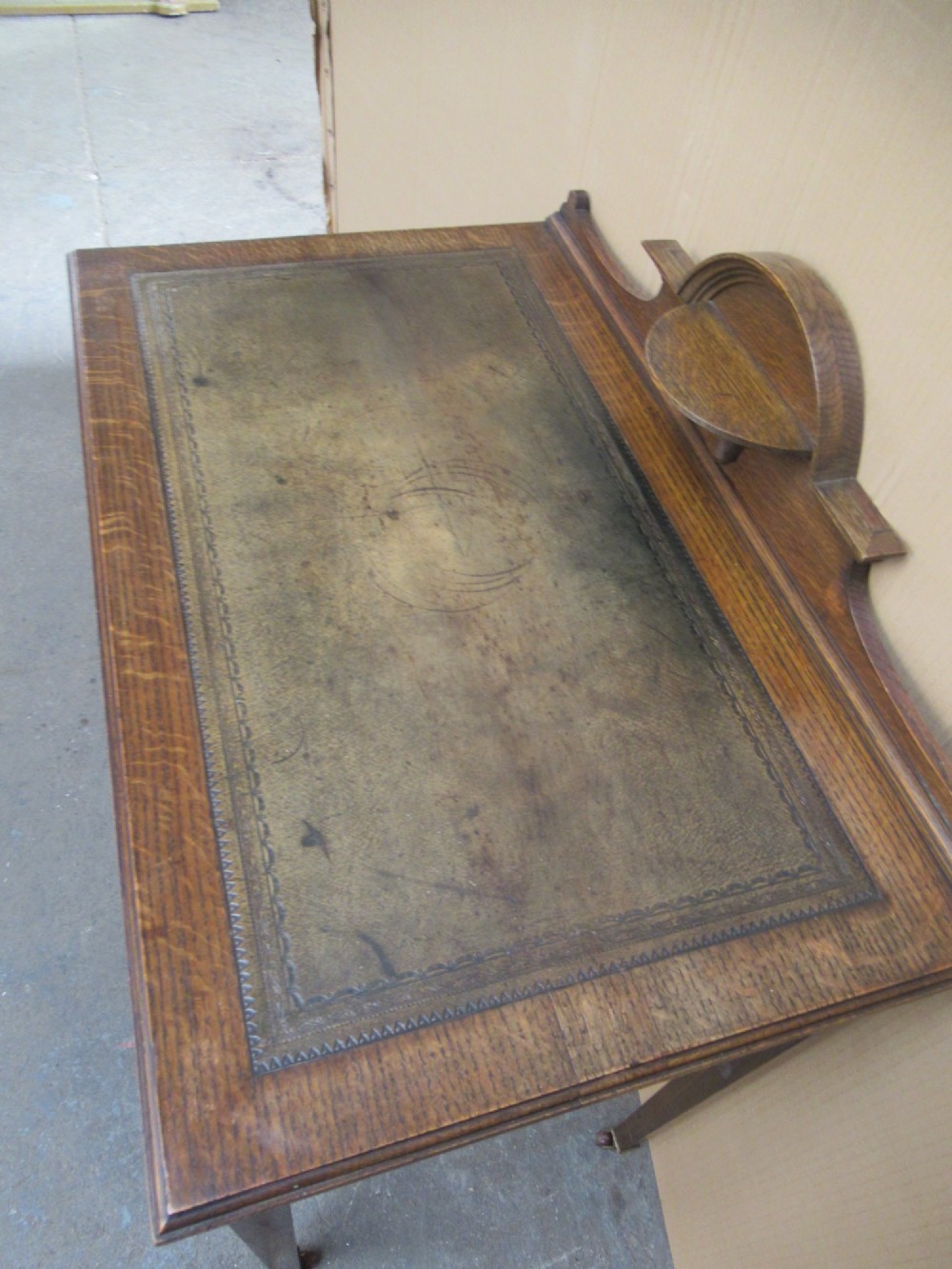 An Edwardian oak writing desk with a leather inset top, three drawers with brass handles, and a raised gallery back featuring a small bracket shelf. View VI