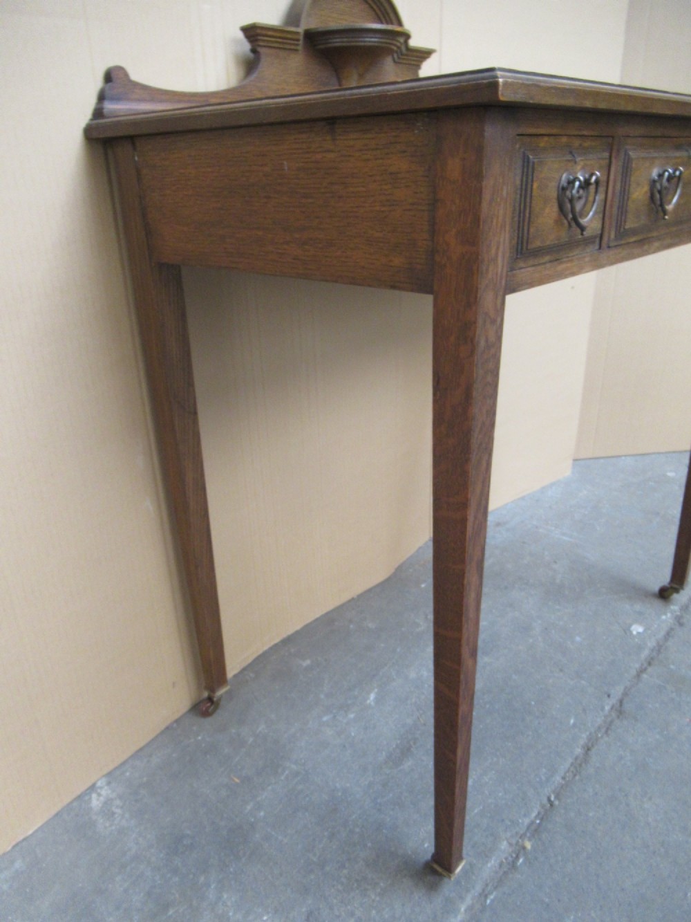 An Edwardian oak writing desk with a leather inset top, three drawers with brass handles, and a raised gallery back featuring a small bracket shelf. View VII