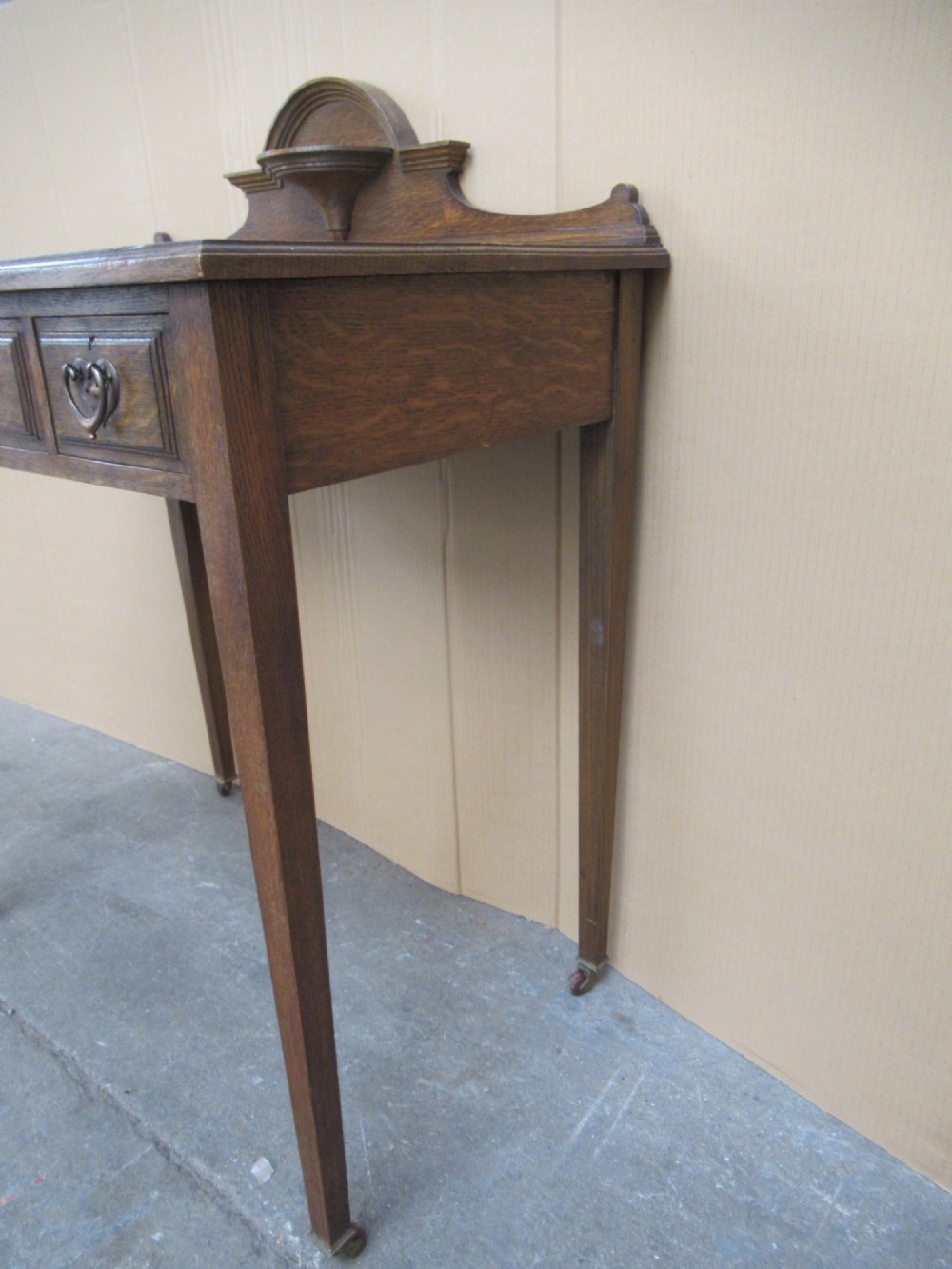 An Edwardian oak writing desk with a leather inset top, three drawers with brass handles, and a raised gallery back featuring a small bracket shelf. View VIII