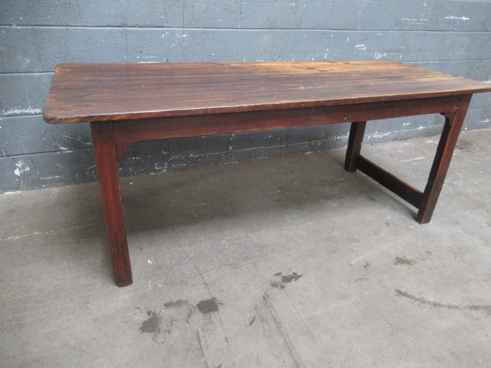 A 19th-century pine dining table with a wide plank top, straight legs, and side stretchers in a warm brown timber finish.