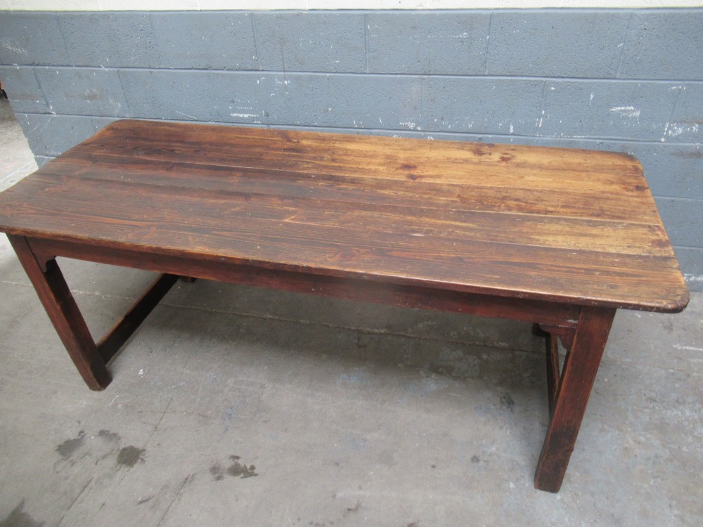 A 19th-century pine dining table with a wide plank top, straight legs, and side stretchers in a warm brown timber finish. View V