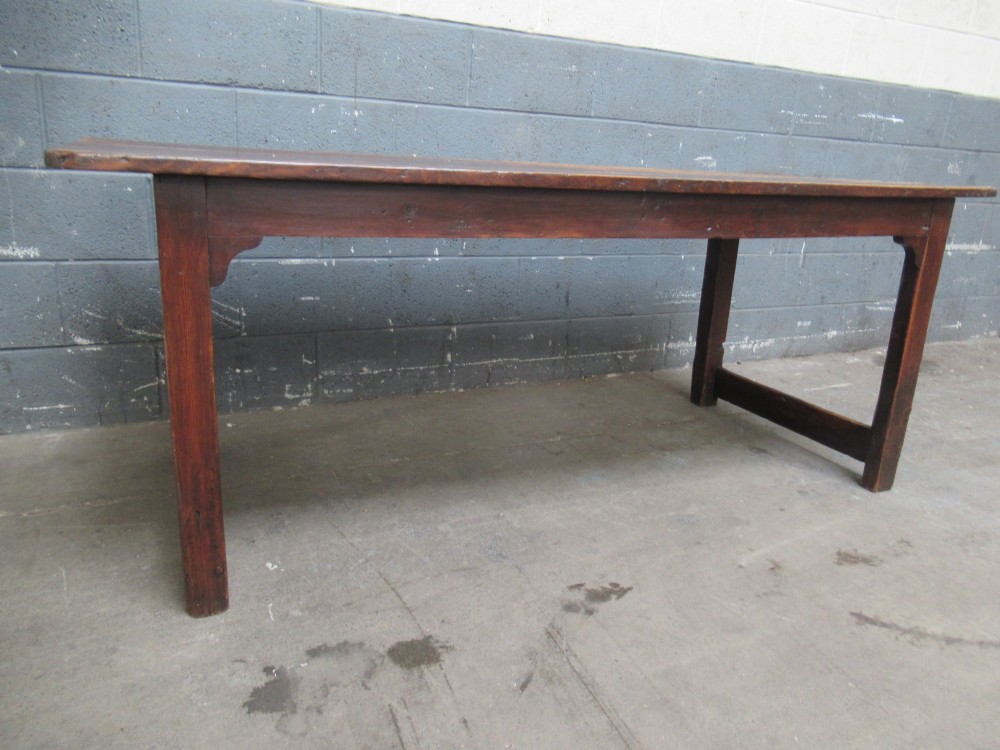 A 19th-century pine dining table with a wide plank top, straight legs, and side stretchers in a warm brown timber finish. View X