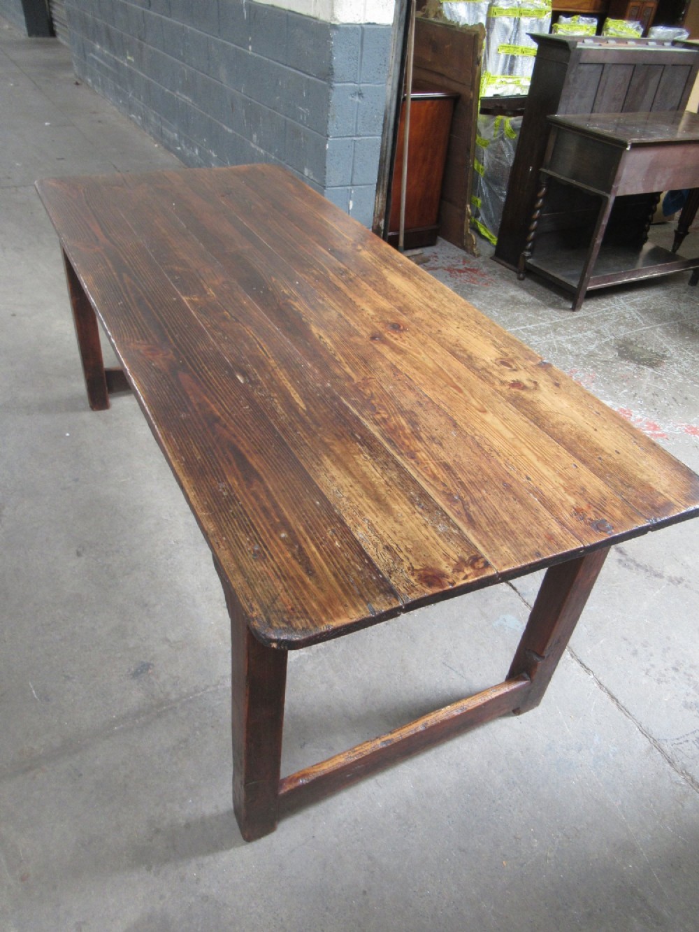 A 19th-century pine dining table with a wide plank top, straight legs, and side stretchers in a warm brown timber finish. View XI