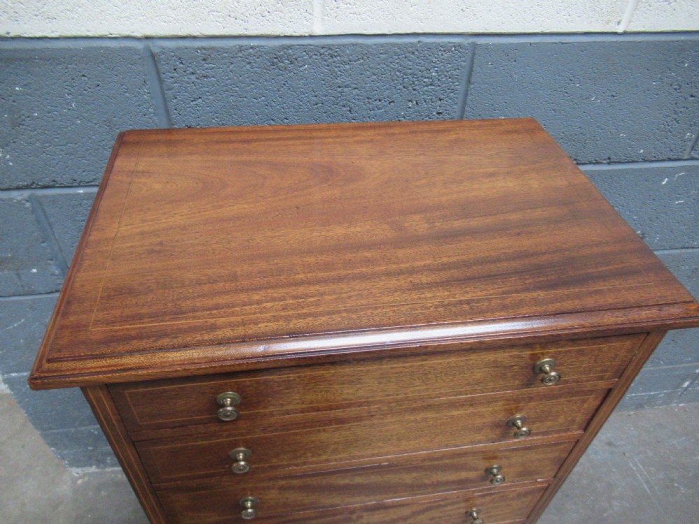 An Edwardian mahogany tall and slim chest featuring seven drawers with brass ring handles set on a solid plinth base. View VI
