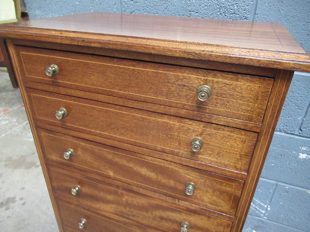 An Edwardian mahogany tall and slim chest featuring seven drawers with brass ring handles set on a solid plinth base. View IX