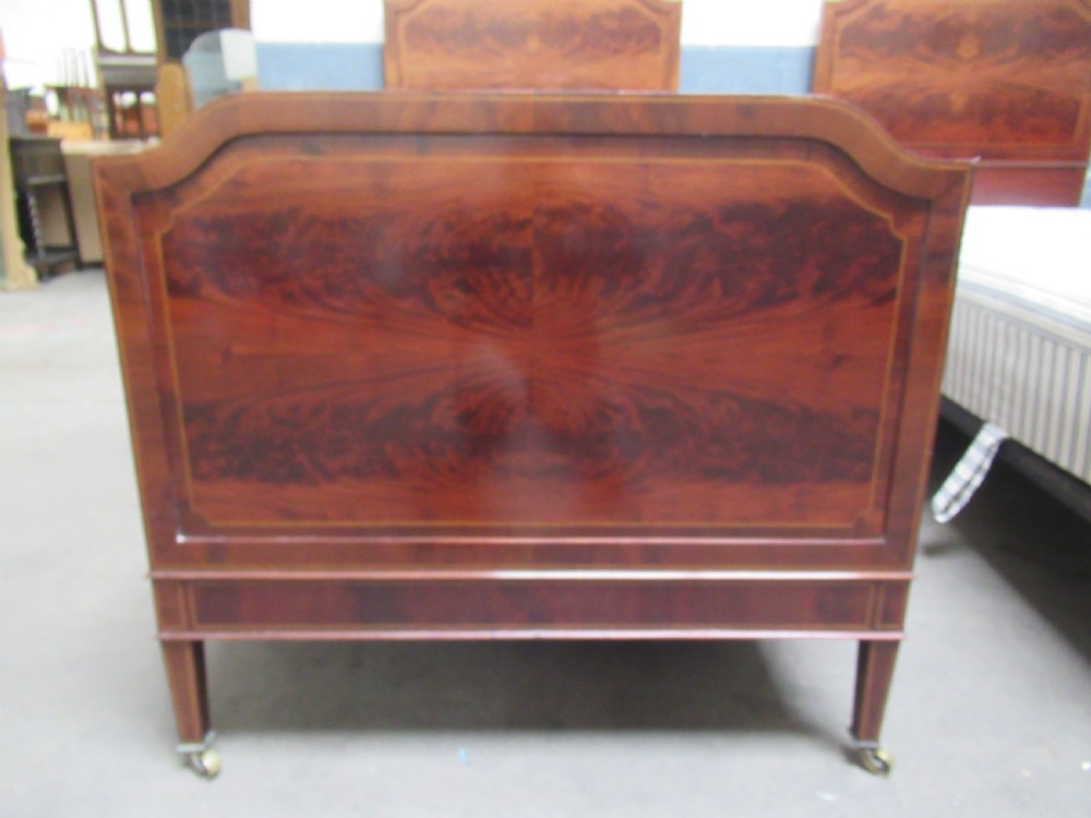 A pair of Edwardian mahogany single beds featuring flame mahogany panels, fine boxwood inlay, and tapered square legs with brass castors. View III
