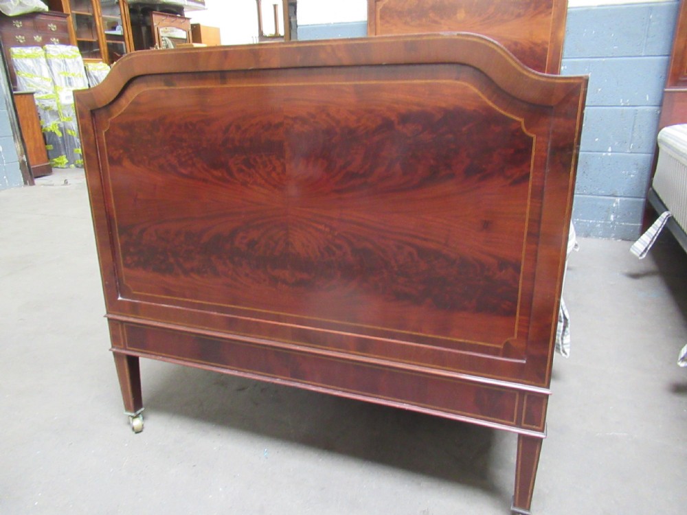 A pair of Edwardian mahogany single beds featuring flame mahogany panels, fine boxwood inlay, and tapered square legs with brass castors. View VII