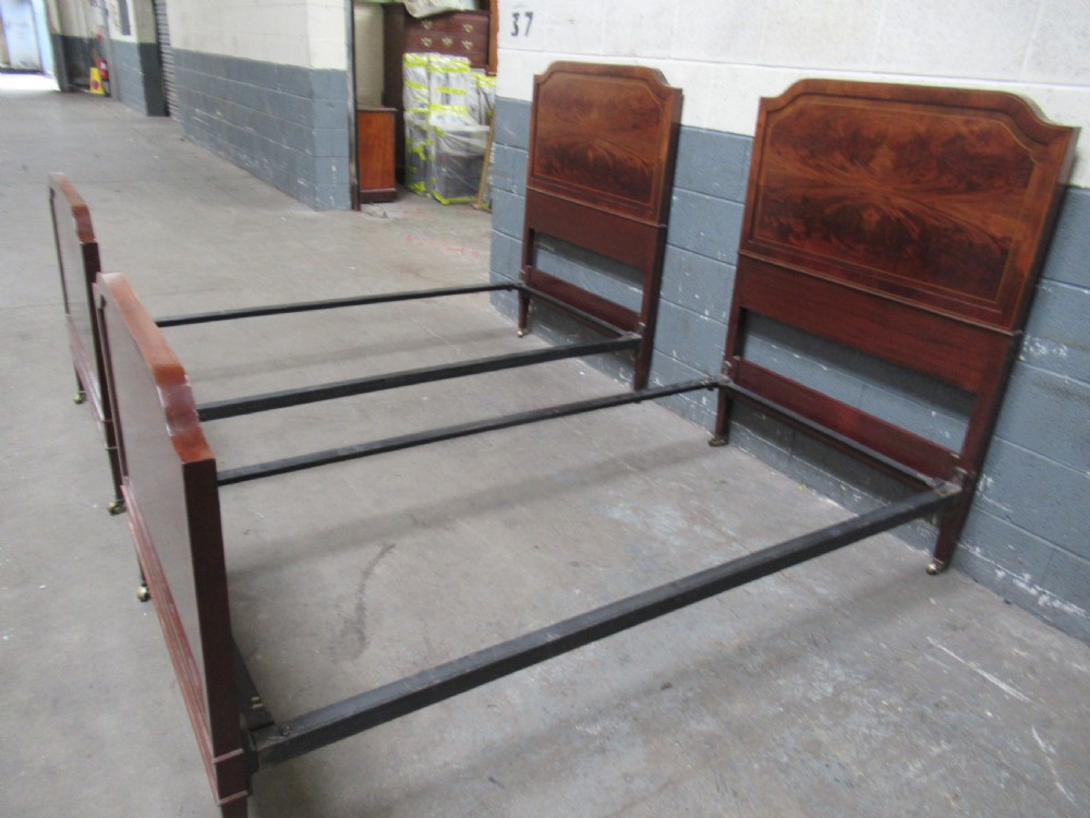 A pair of Edwardian mahogany single beds featuring flame mahogany panels, fine boxwood inlay, and tapered square legs with brass castors. View VIII