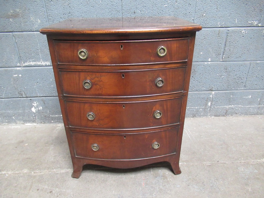 A small Georgian style mahogany bowfront chest of drawers featuring four graduated drawers with circular brass drop handles and bracket feet.