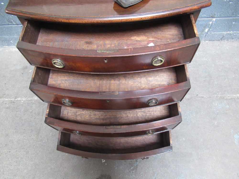 A small Georgian style mahogany bowfront chest of drawers featuring four graduated drawers with circular brass drop handles and bracket feet. View VI