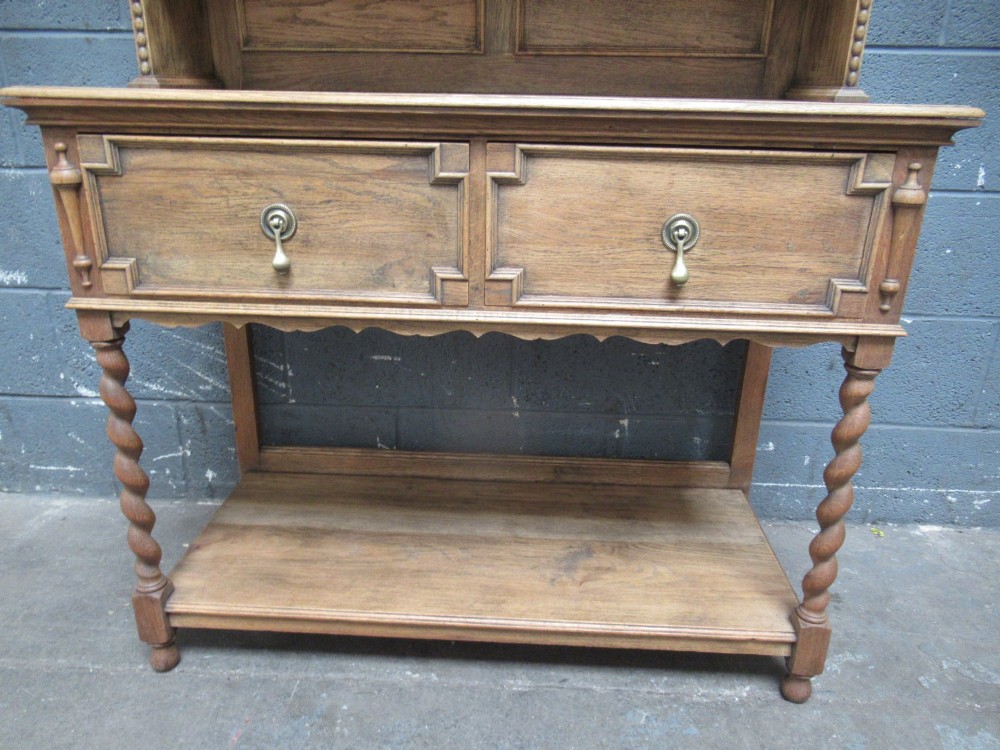 A 1920s oak two-door glazed bookcase featuring upper glass display cabinet, two geometric-moulded drawers, and barley twist legs with a lower undertier shelf. View VII