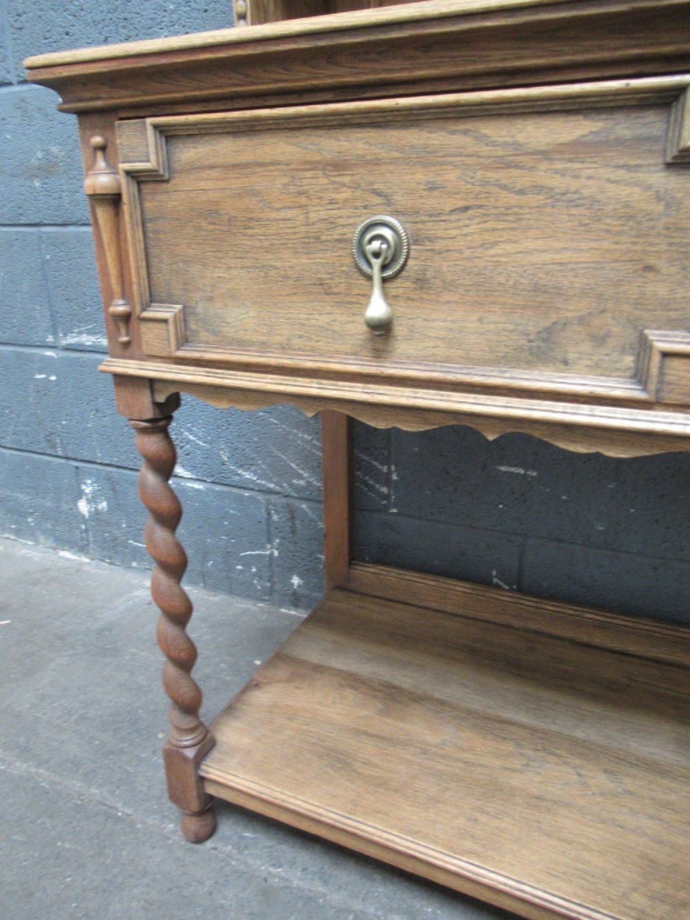 A 1920s oak two-door glazed bookcase featuring upper glass display cabinet, two geometric-moulded drawers, and barley twist legs with a lower undertier shelf. View IX