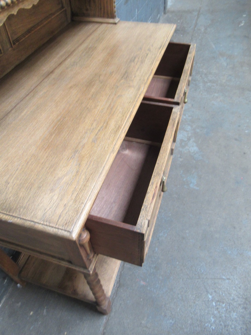 A 1920s oak two-door glazed bookcase featuring upper glass display cabinet, two geometric-moulded drawers, and barley twist legs with a lower undertier shelf. View X