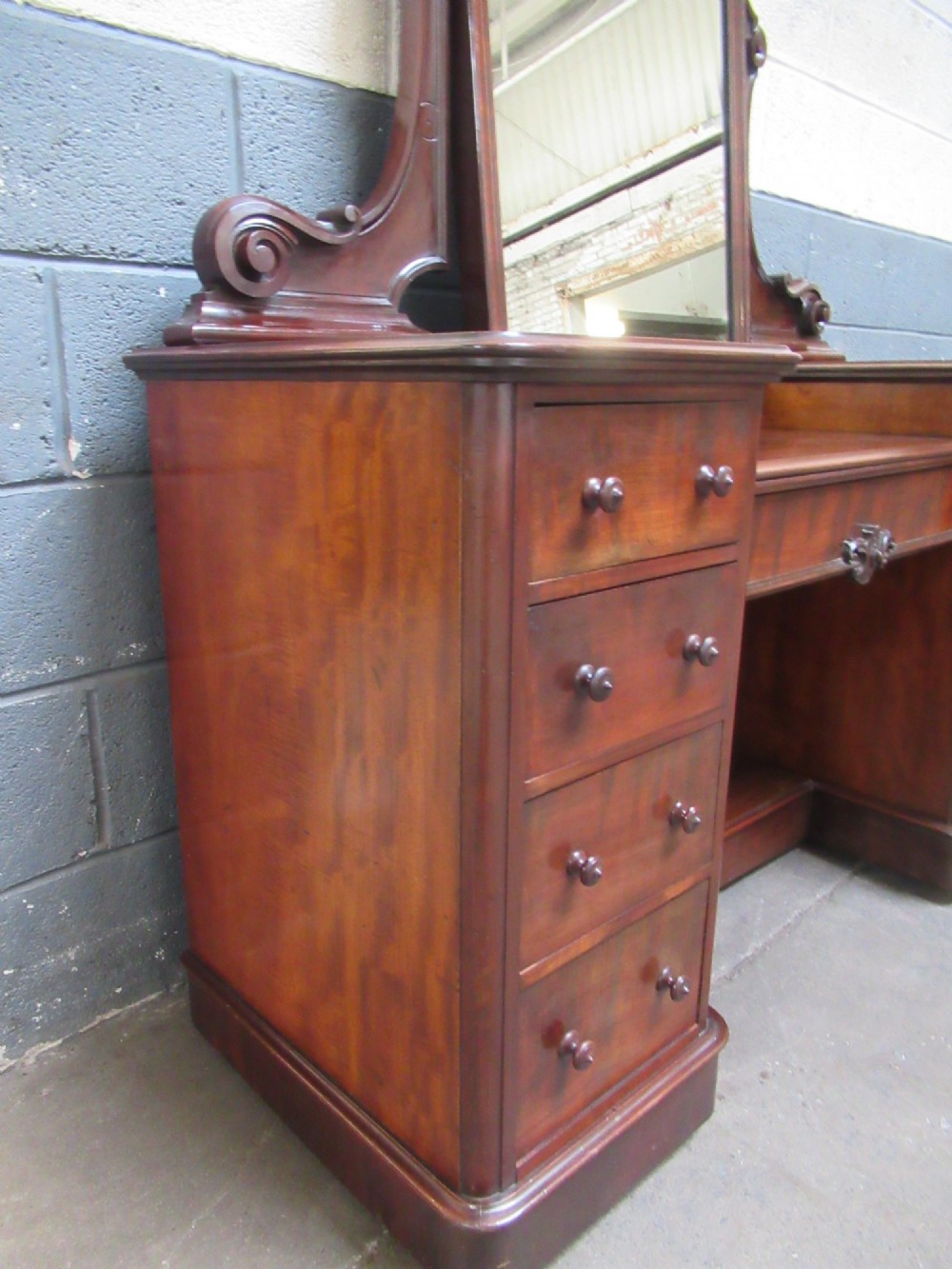 A Victorian mahogany dressing table featuring a central arched swing mirror with carved scroll supports, set above twin pedestals containing drawers with turned wooden handles. View III
