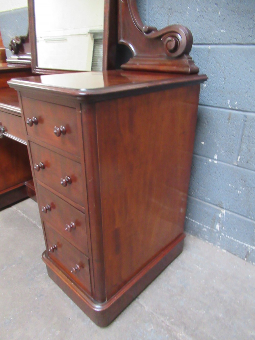 A Victorian mahogany dressing table featuring a central arched swing mirror with carved scroll supports, set above twin pedestals containing drawers with turned wooden handles. View IV