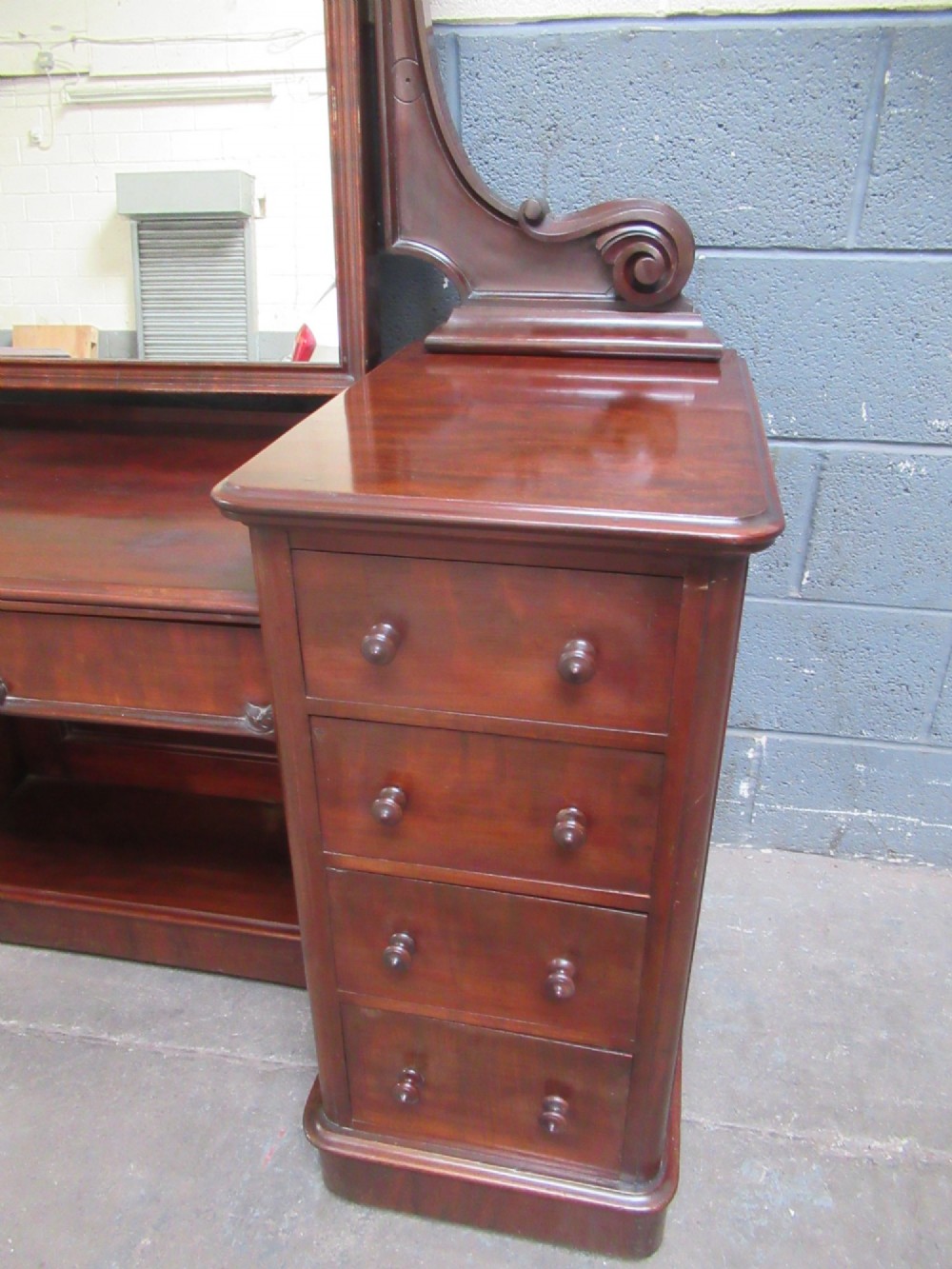 A Victorian mahogany dressing table featuring a central arched swing mirror with carved scroll supports, set above twin pedestals containing drawers with turned wooden handles. View V
