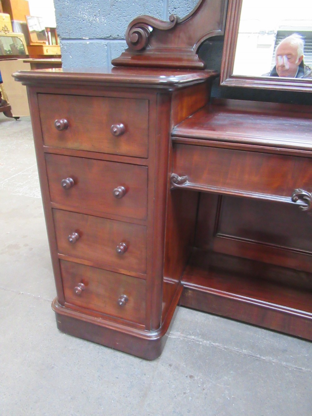 A Victorian mahogany dressing table featuring a central arched swing mirror with carved scroll supports, set above twin pedestals containing drawers with turned wooden handles. View VI